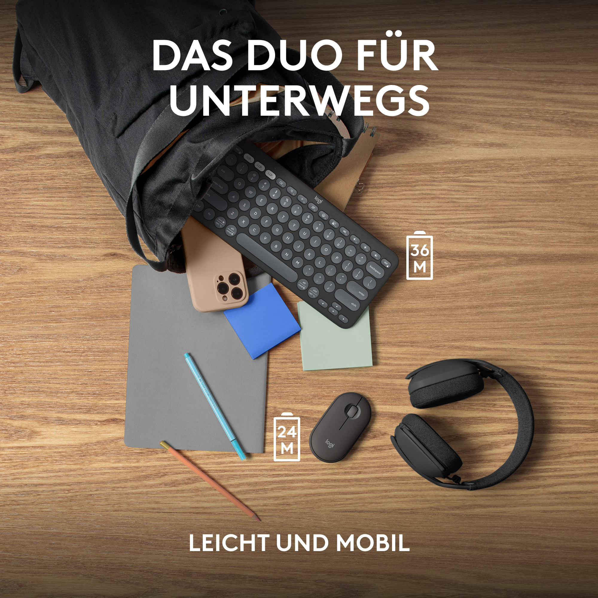 Schwarze Tastatur, Maus, Telefon und Notizbuch auf Holzoberfläche.