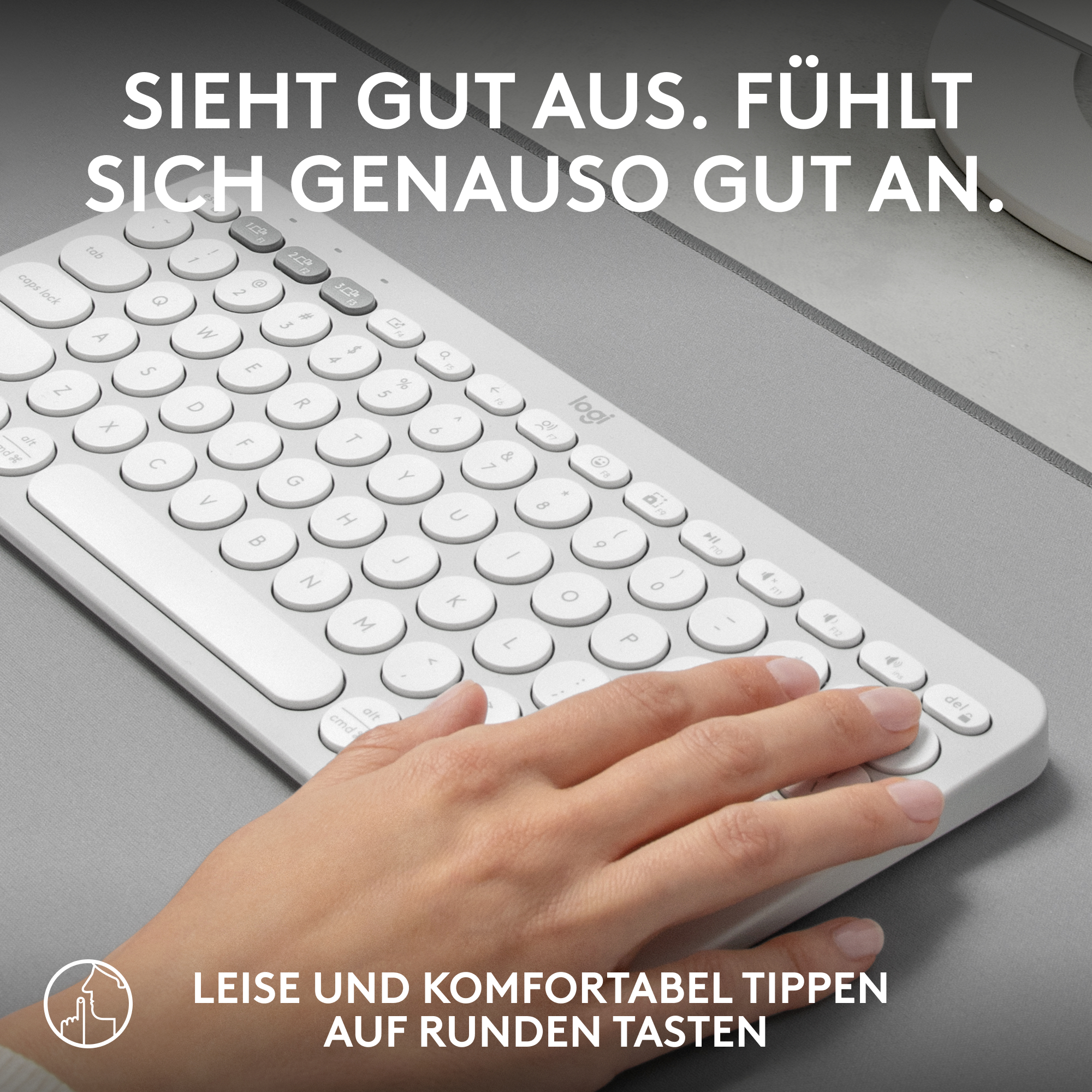 Weiße Tastatur mit abgerundeten Tasten. Hand tippt. Graue Oberfläche.