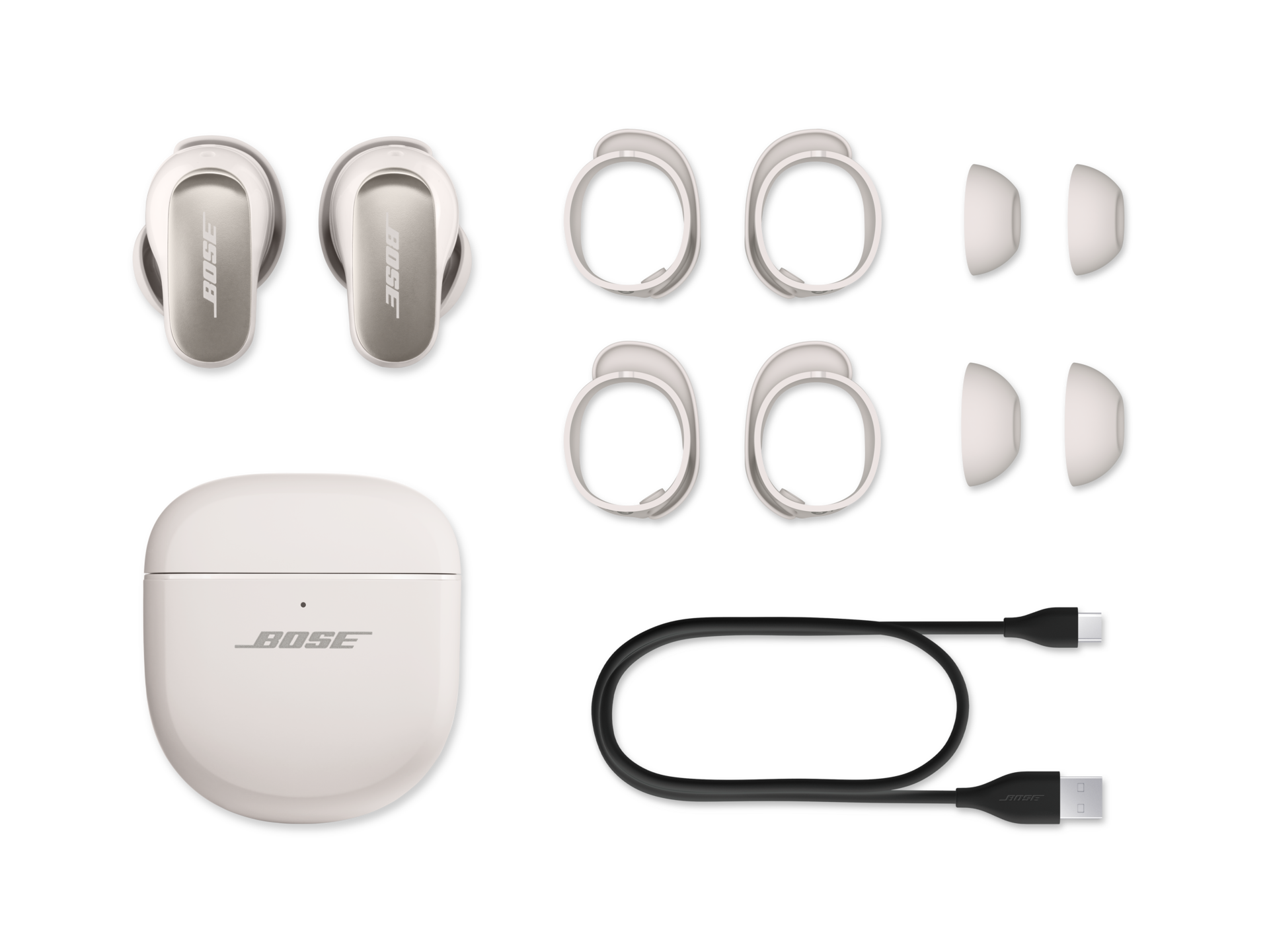 Bose-Kopfhörer, Ladecase, Ohrstöpsel und ein Ladekabel auf schwarzem Hintergrund.