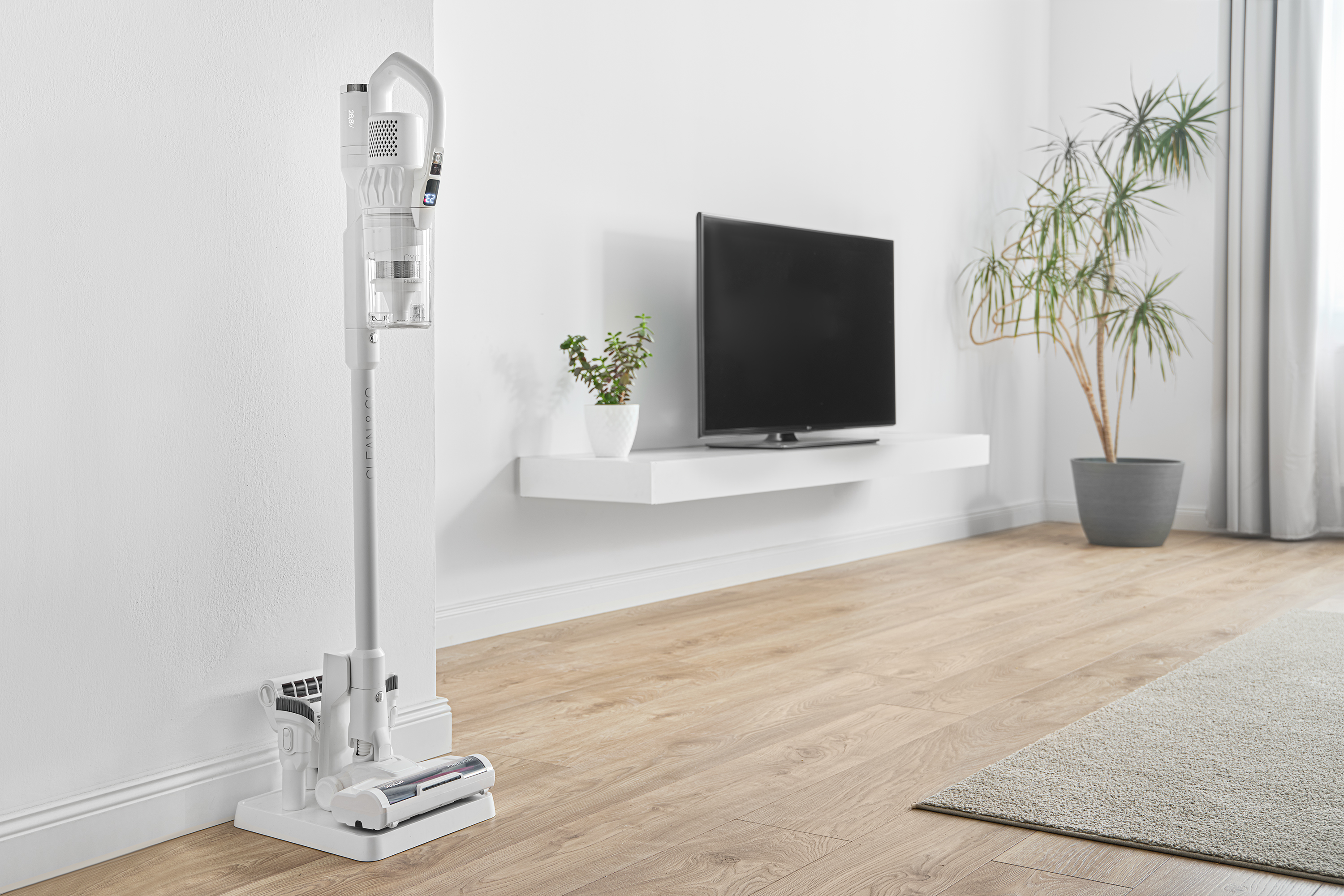 Fehér vezeték nélküli porszívó töltőállomáson, modern nappali környezetben.