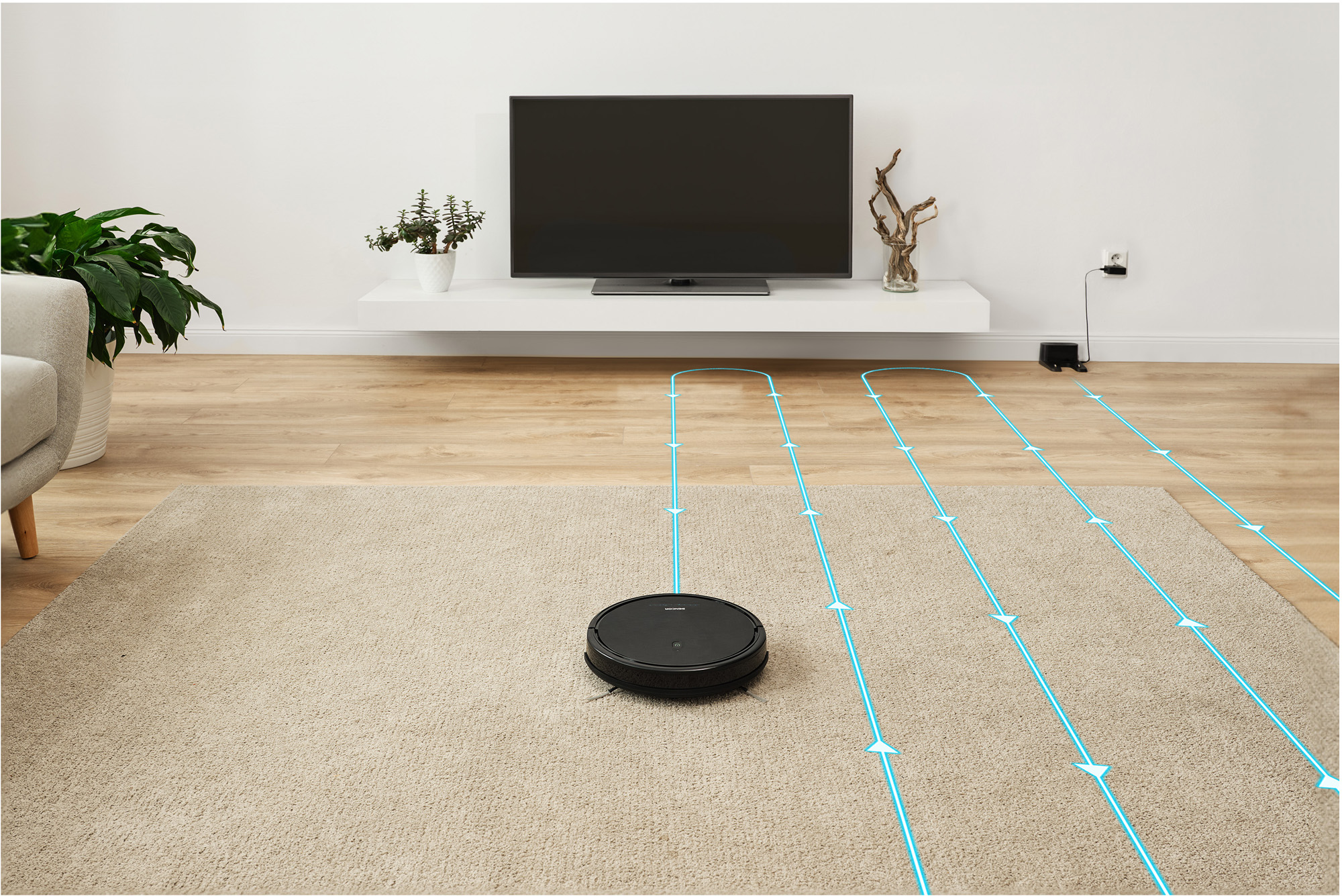 Robotporszívó szőnyegen, kék útmutató vonalakkal. TV a falon a háttérben.