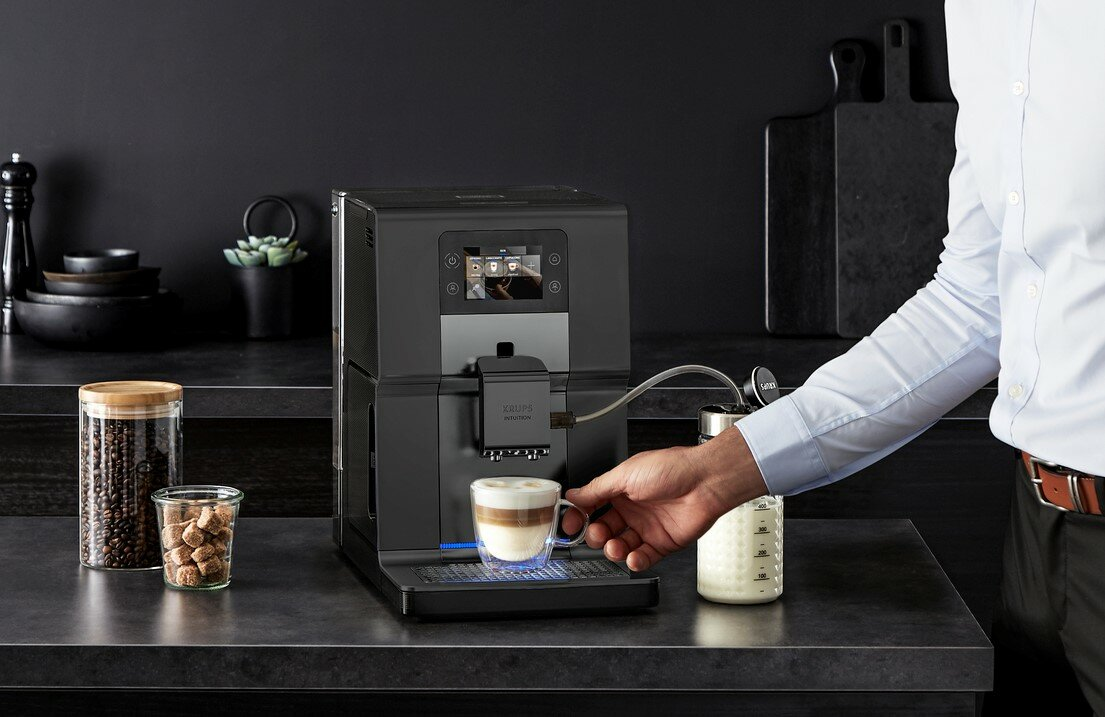 Osoba robiąca kawę czarno-srebrnym ekspresem do kawy.