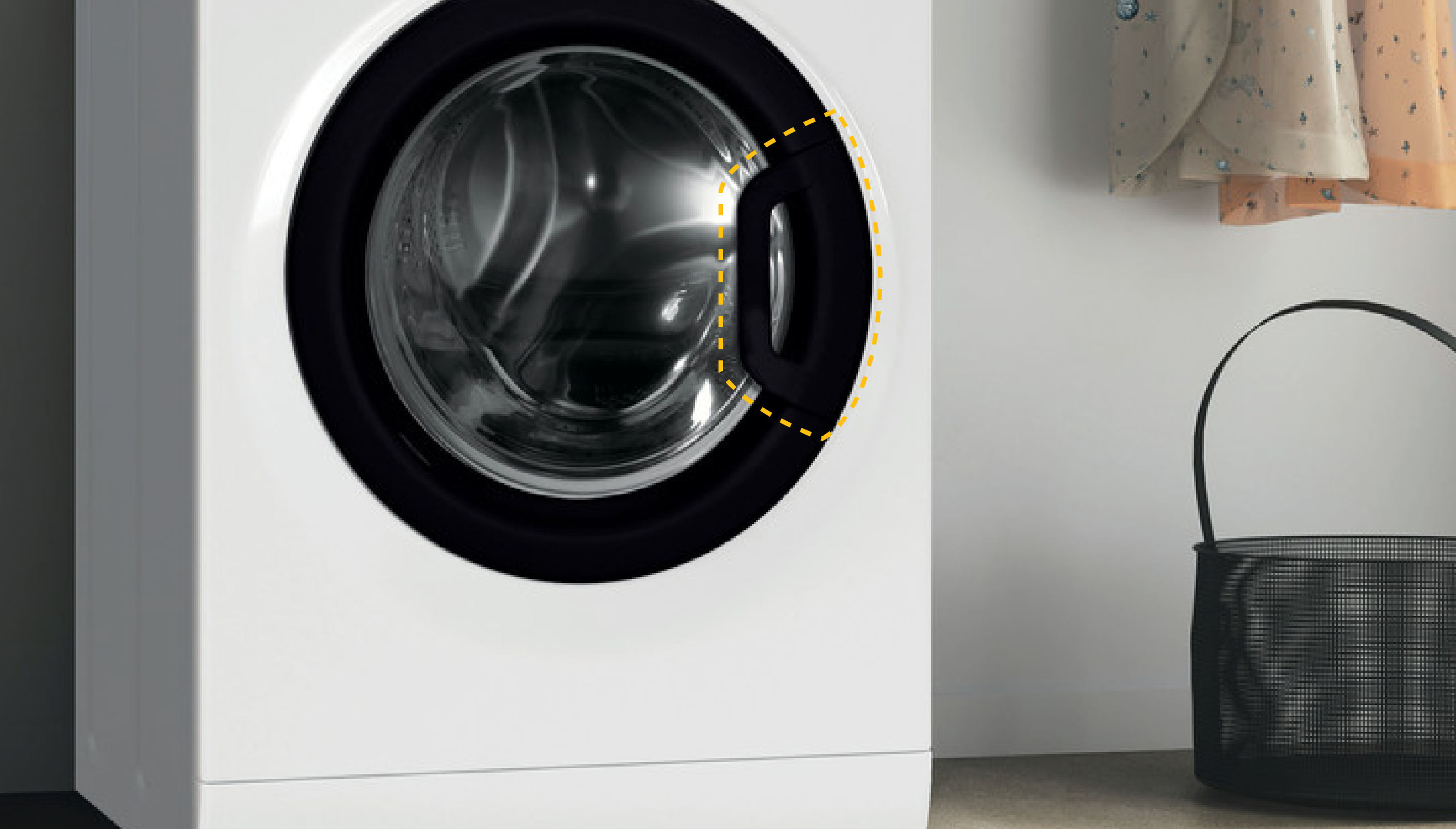 Biała pralka z czarnymi drzwiami i bębnem. Obok kosz.