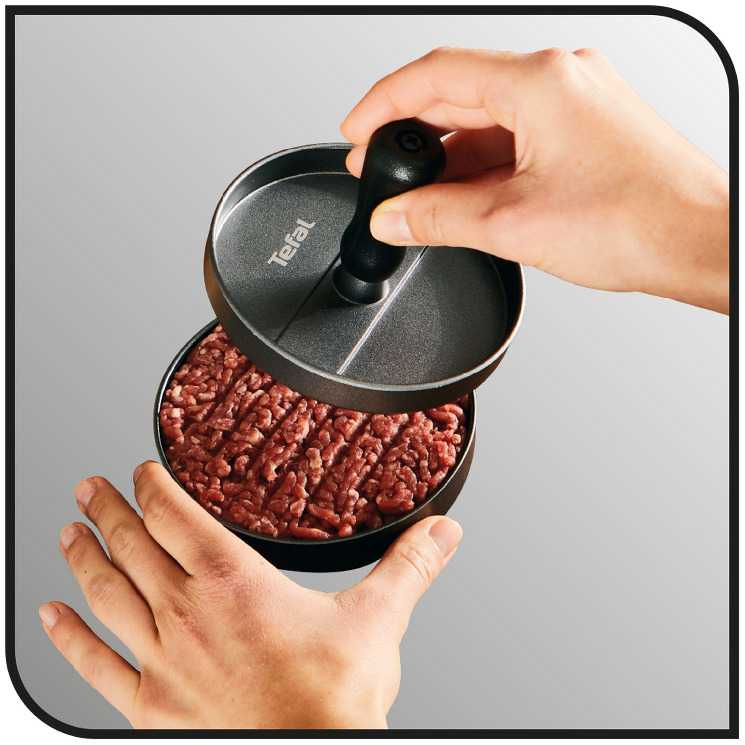 Hands pressing a burger patty maker.