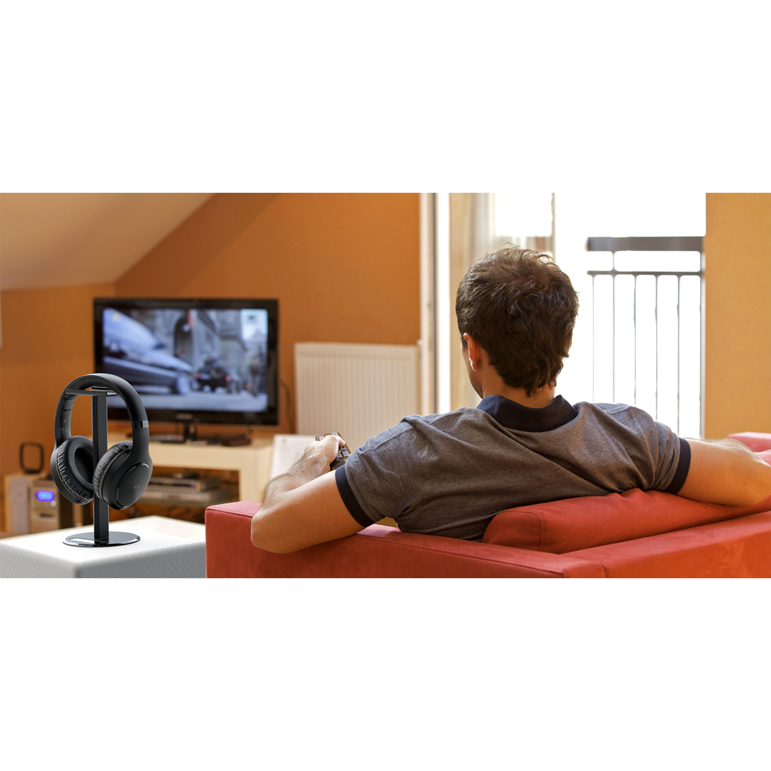 Un uomo guarda la TV, con le cuffie su un supporto a sinistra.