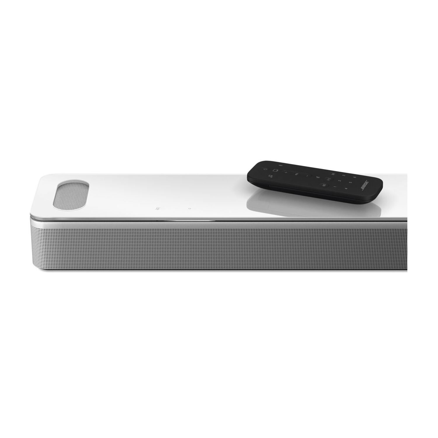 Soundbar bianca con telecomando nero su una superficie bianca.