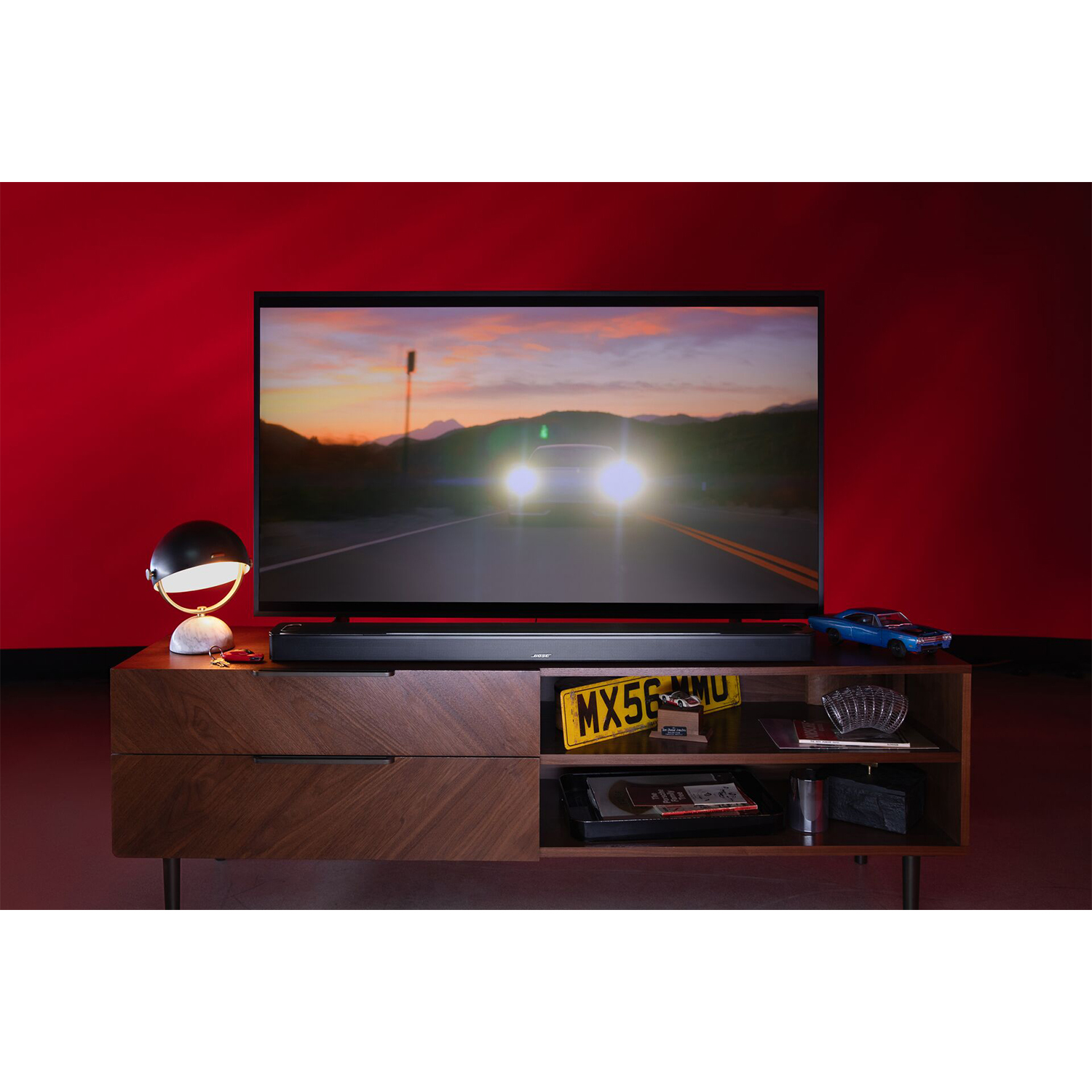 Televisore con auto sullo schermo e soundbar sotto, in una stanza elegante.
