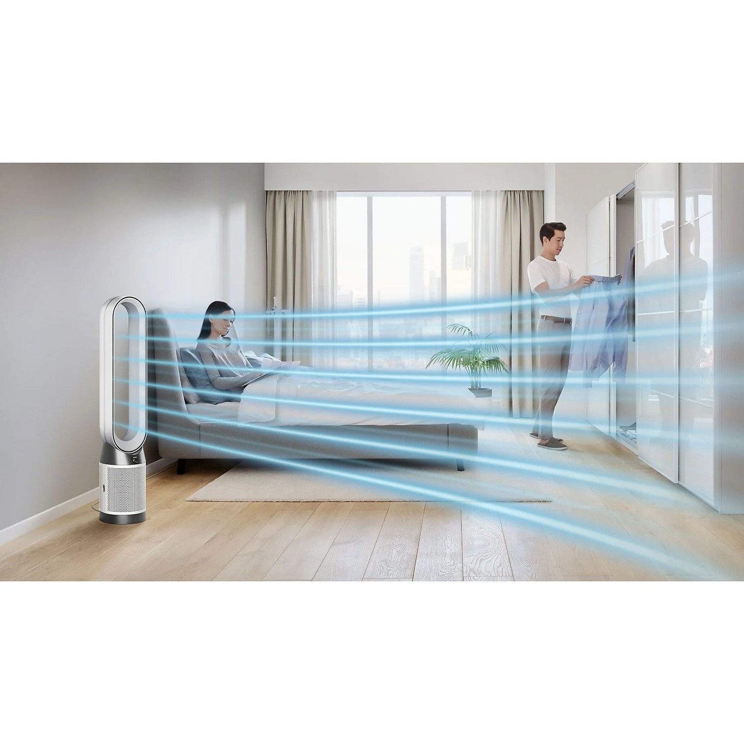 Chambre avec un ventilateur et une femme au lit. Un homme range des vêtements.