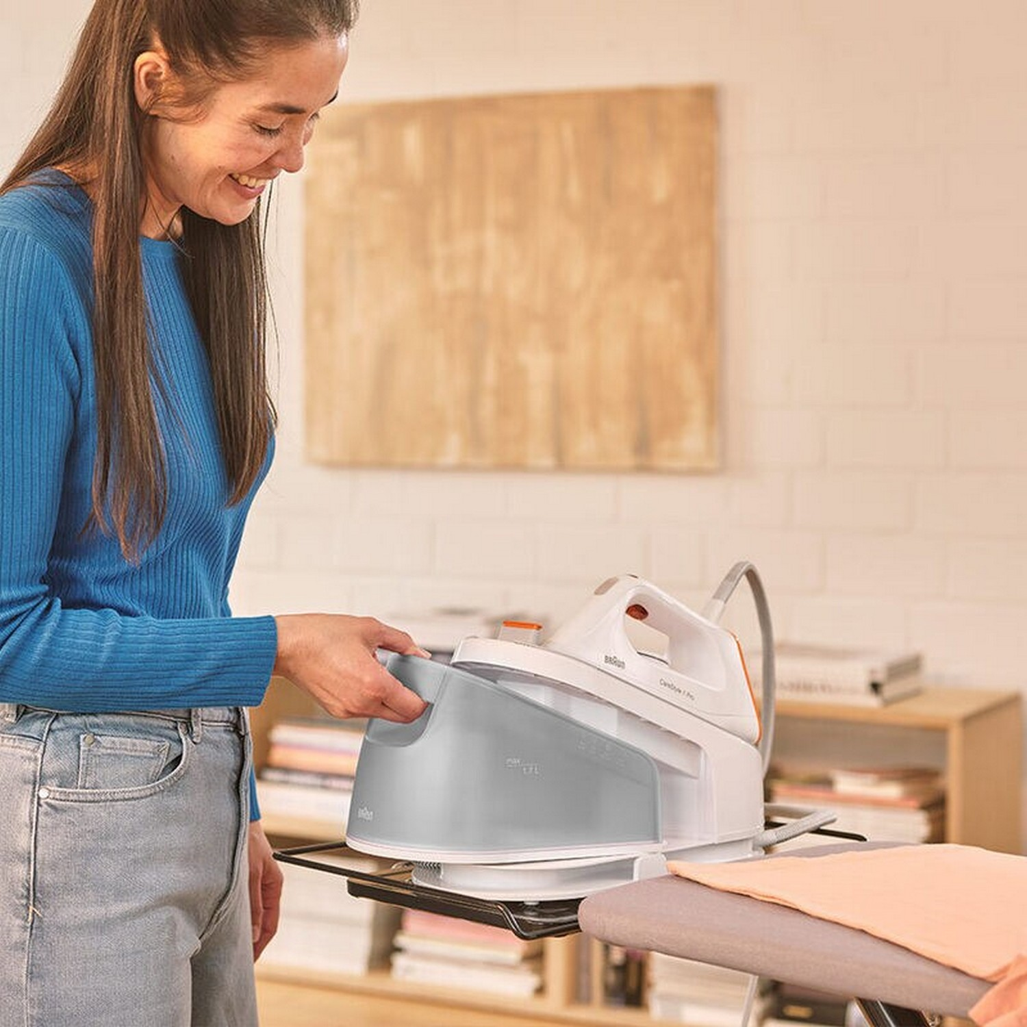 A woman ironing clothes with a steam iron on an ironing board, with a wooden wall in the background.