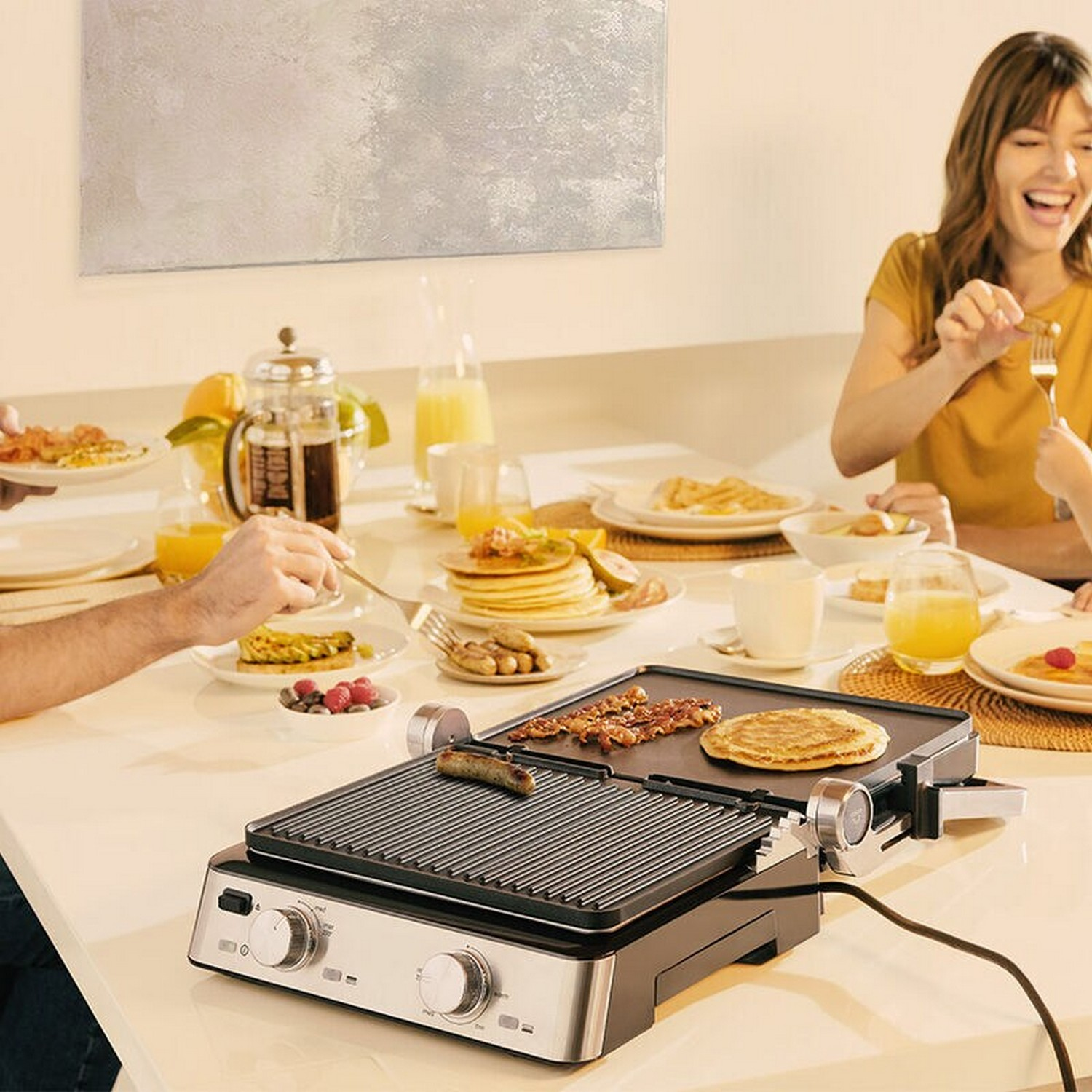 Les gens prennent leur petit déjeuner. Un grill avec de la nourriture sur une table. Une femme rit.