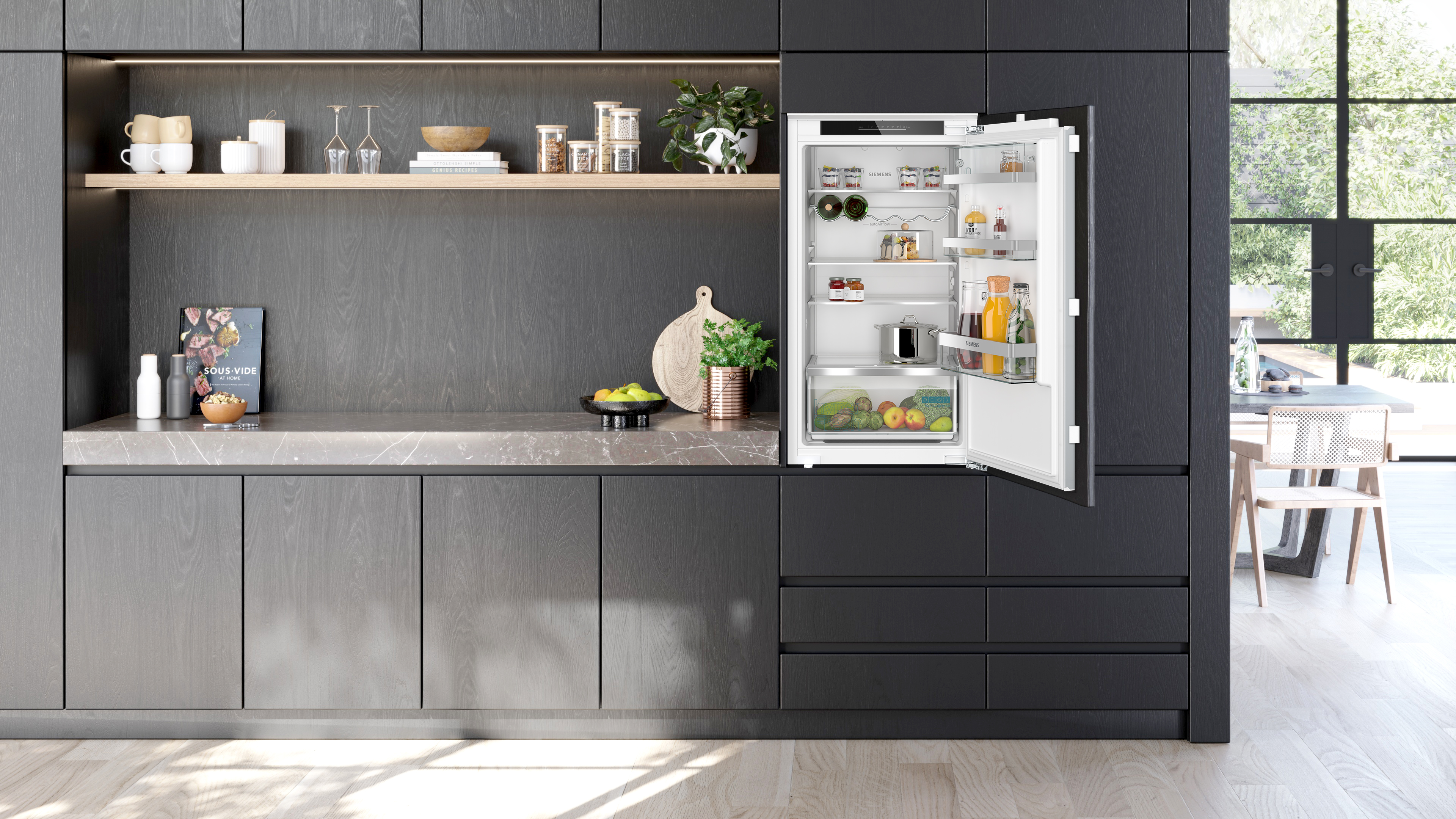 Moderne Küche mit dunklen Holzschränken und offenem Kühlschrank mit Lebensmitteln.