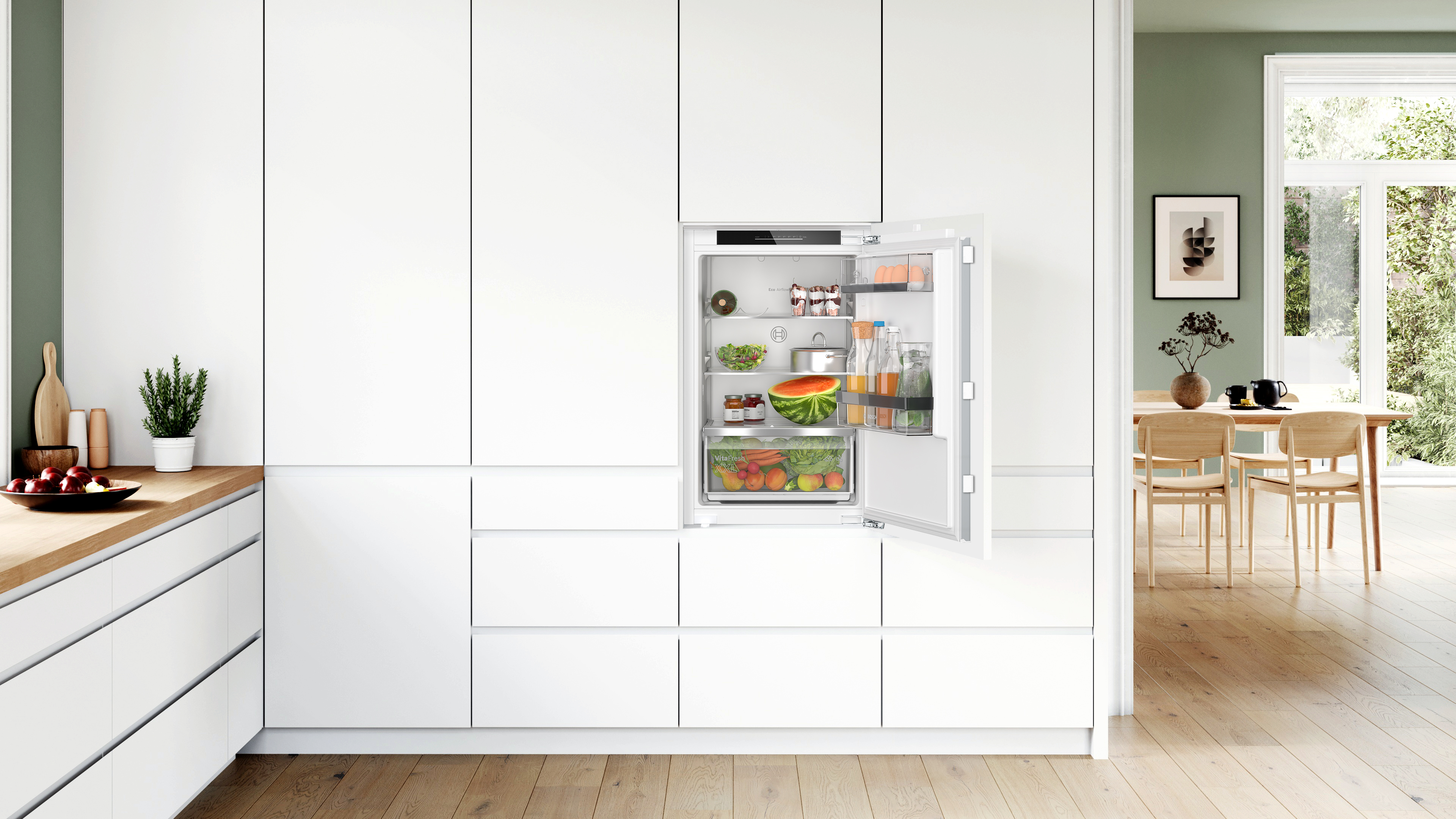 Eine weiße Küche mit einem Kühlschrank mit offener Tür, gefüllt mit Lebensmitteln.