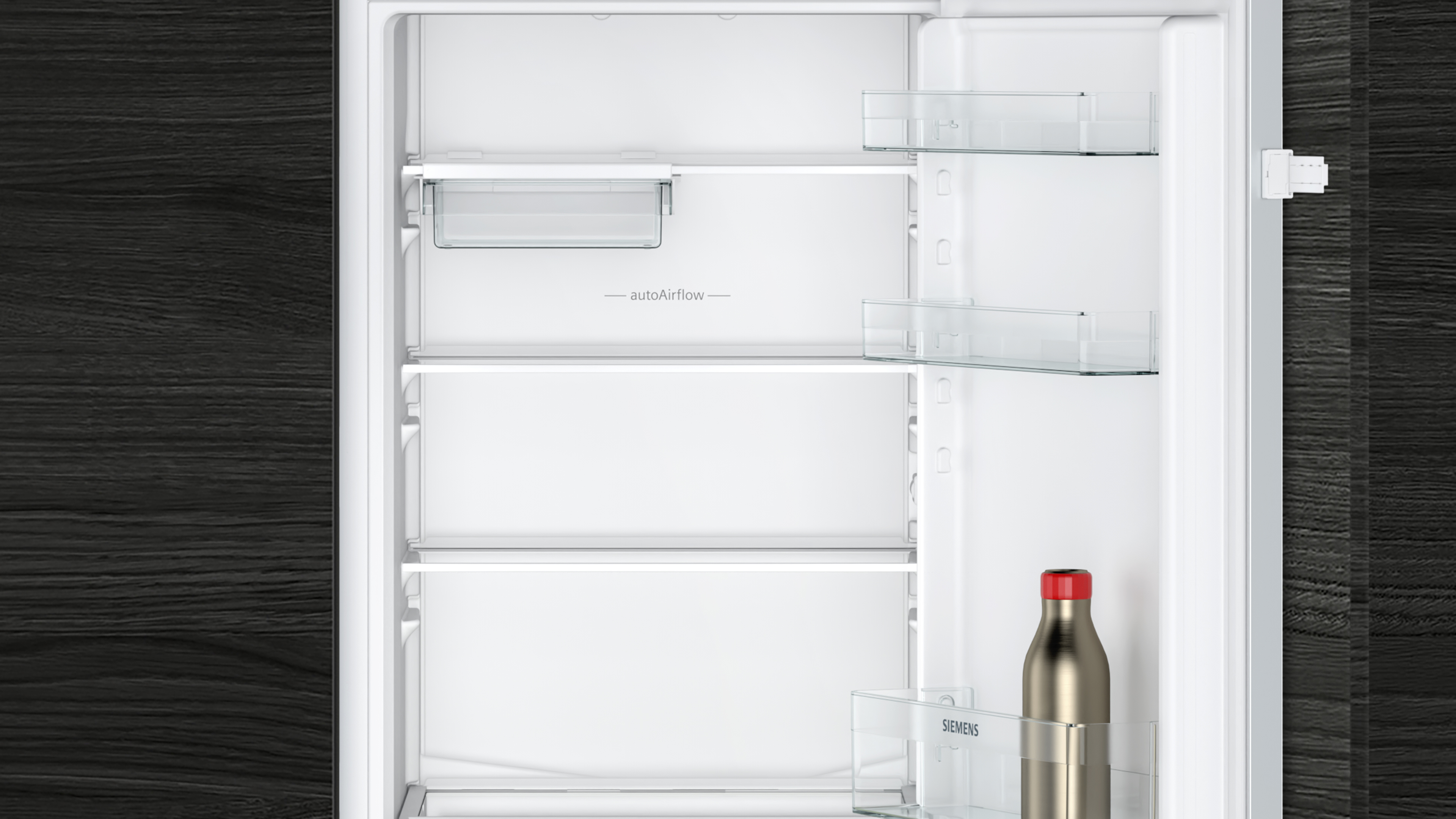 Leeres weißes Kühlschrankinnere mit Glasböden, autoAirflow. Eine Flasche mit roter Kappe steht unten.