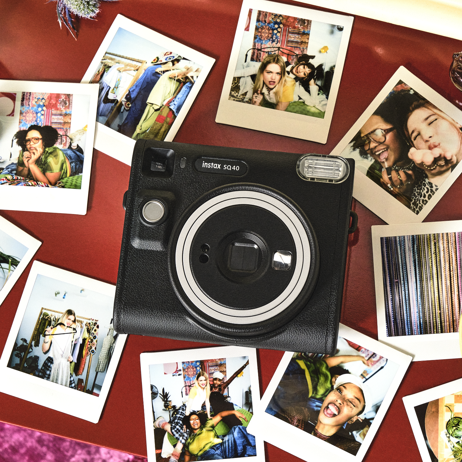 A black Instax SO40 camera surrounded by polaroid photos on a red surface, capturing moments.