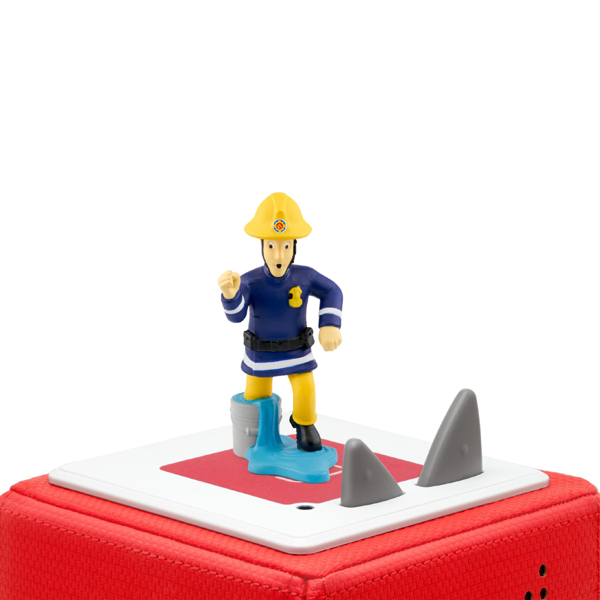 Eine Feuerwehrmann-Spielfigur steht auf einem rot-weißen Quadrat. Zwei graue Haifischflossen sind auf dem Quadrat.