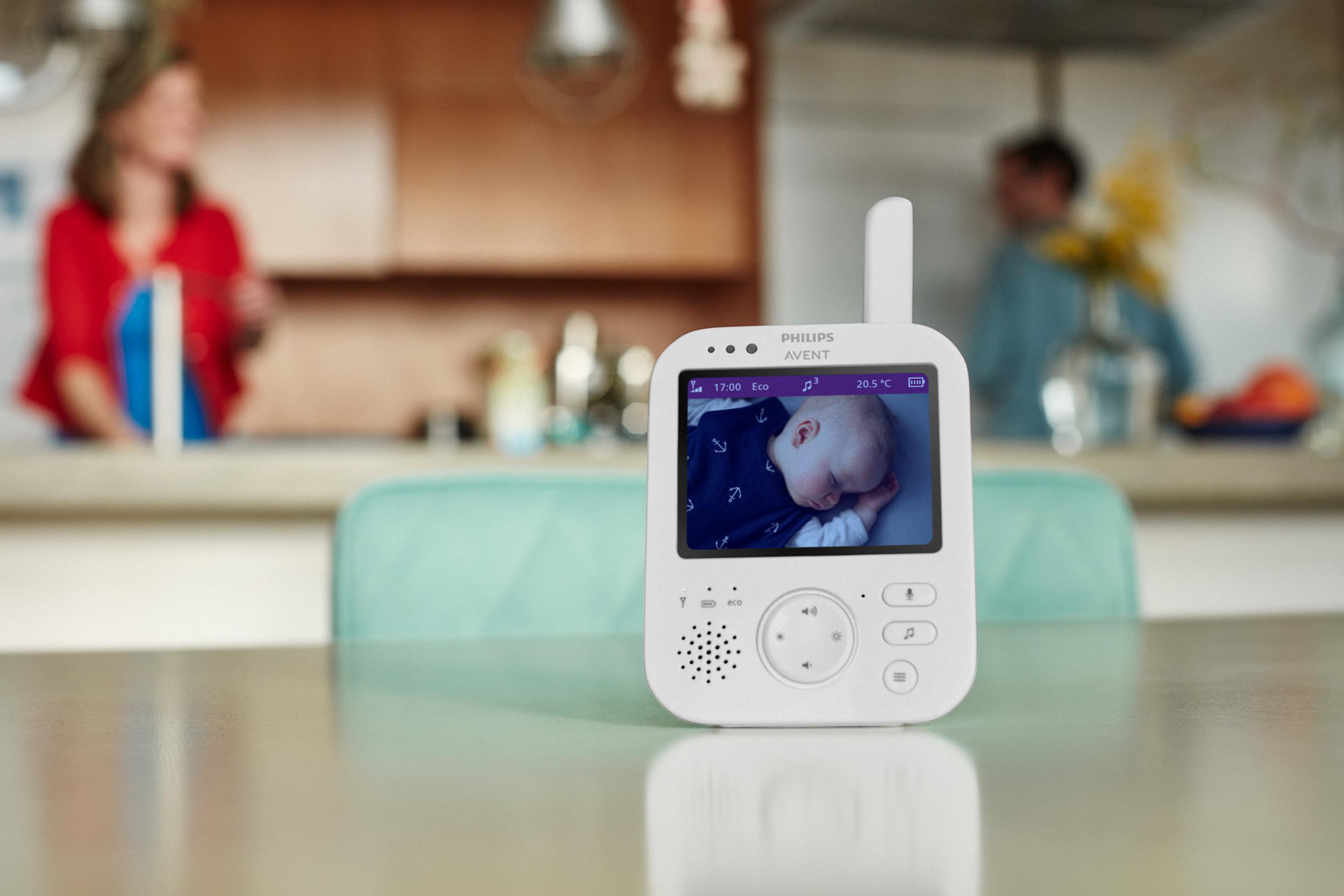 Babyphone mit Babyanzeige. Personen im Hintergrund, Küchenszene.