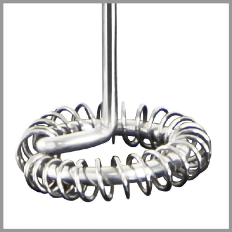 Zbliżenie srebrnego spieniacza do mleka ze spiralnym wzorem.