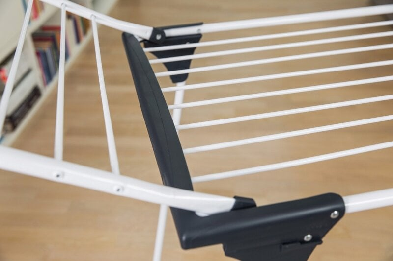 Biała suszarka do ubrań, częściowo otwarta. Tło jest rozmyte.