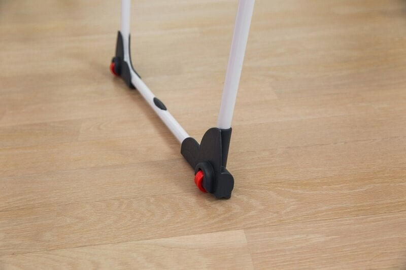 Rama i koła składanego chodzika na drewnianej podłodze. Rama jest biała, z czarnymi przegubami.