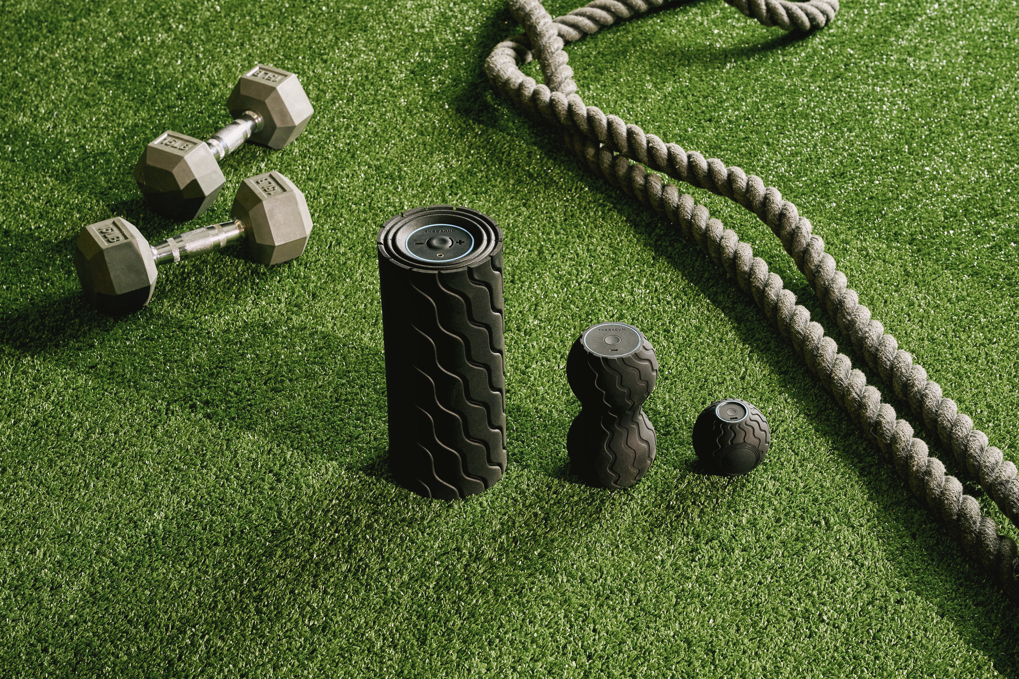 Fitnessgeräte auf grünem Rasen: Gewichte, Rolle, Seil.