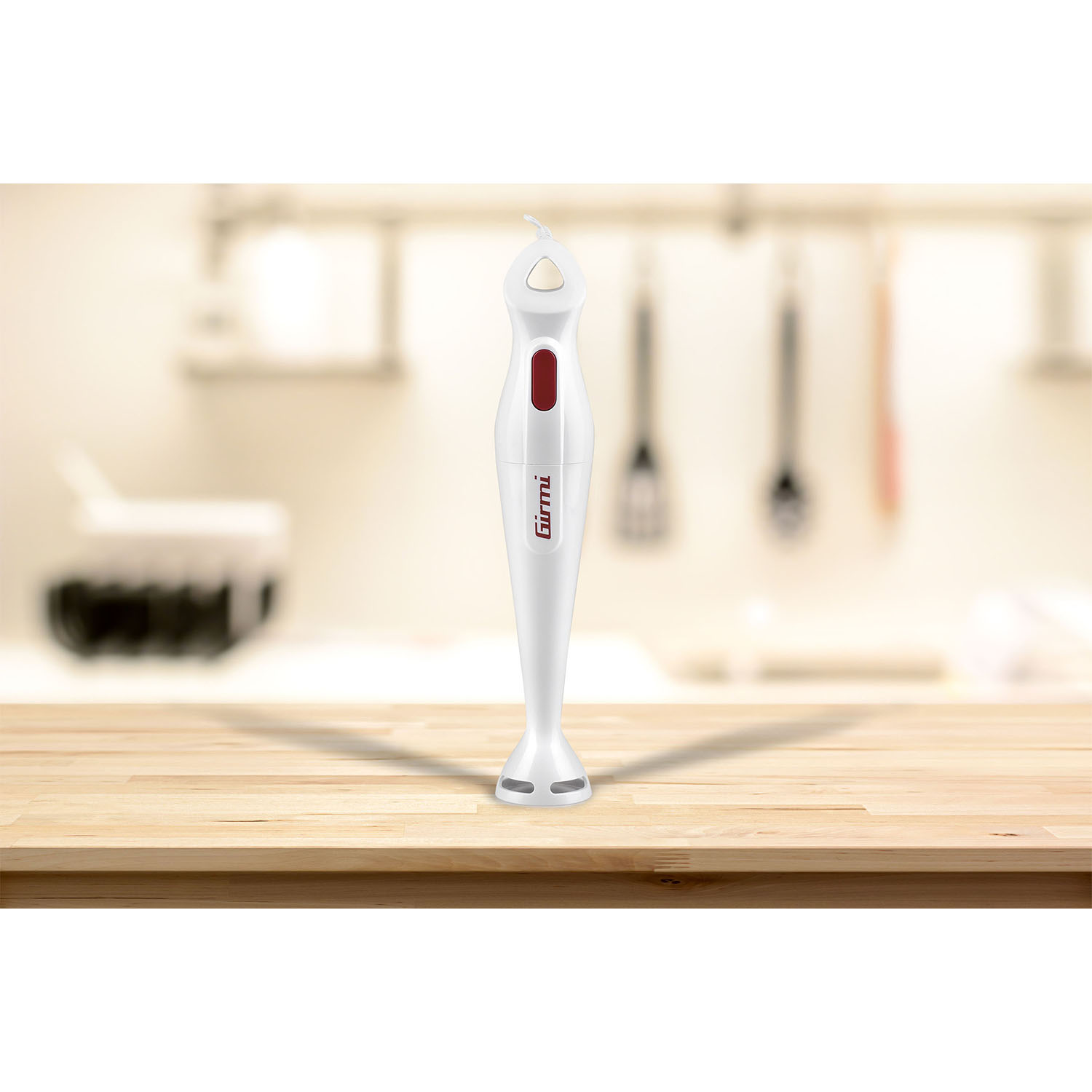 Un frullatore a immersione bianco su una superficie di legno, con sfondo cucina sfocato.