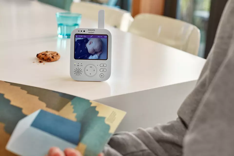 Babyfon mit Bildschirm, der ein schlafendes Baby zeigt, auf einem weißen Tisch.
