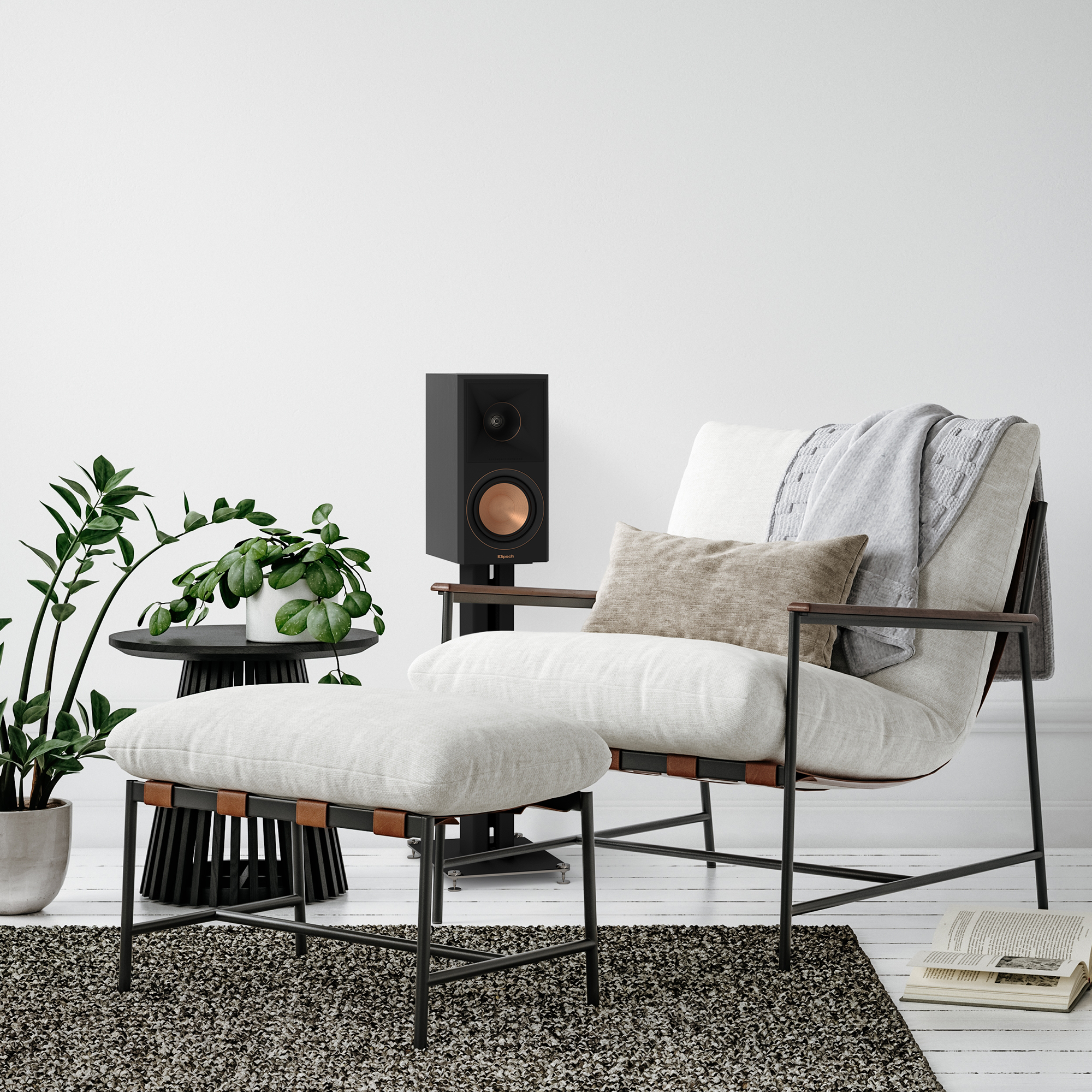 Wohnzimmer mit Sessel, Hocker, Lautsprecher, Topfpflanze und Teppich.