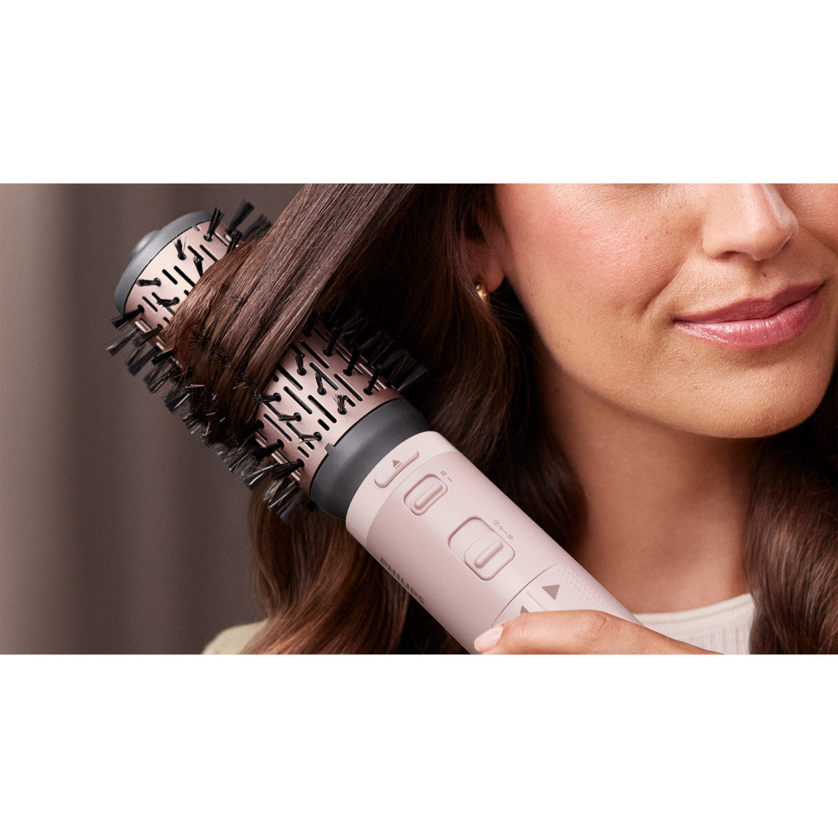 Kobieta używa różowo-czarnego narzędzia do stylizacji włosów. Włosy są stylizowane szczotką.
