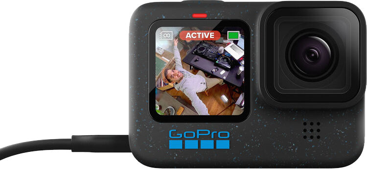 GoPro kamera, amely egy személyt mutat a kijelzőn. A kamera fekete, töltőkábellel csatlakoztatva.