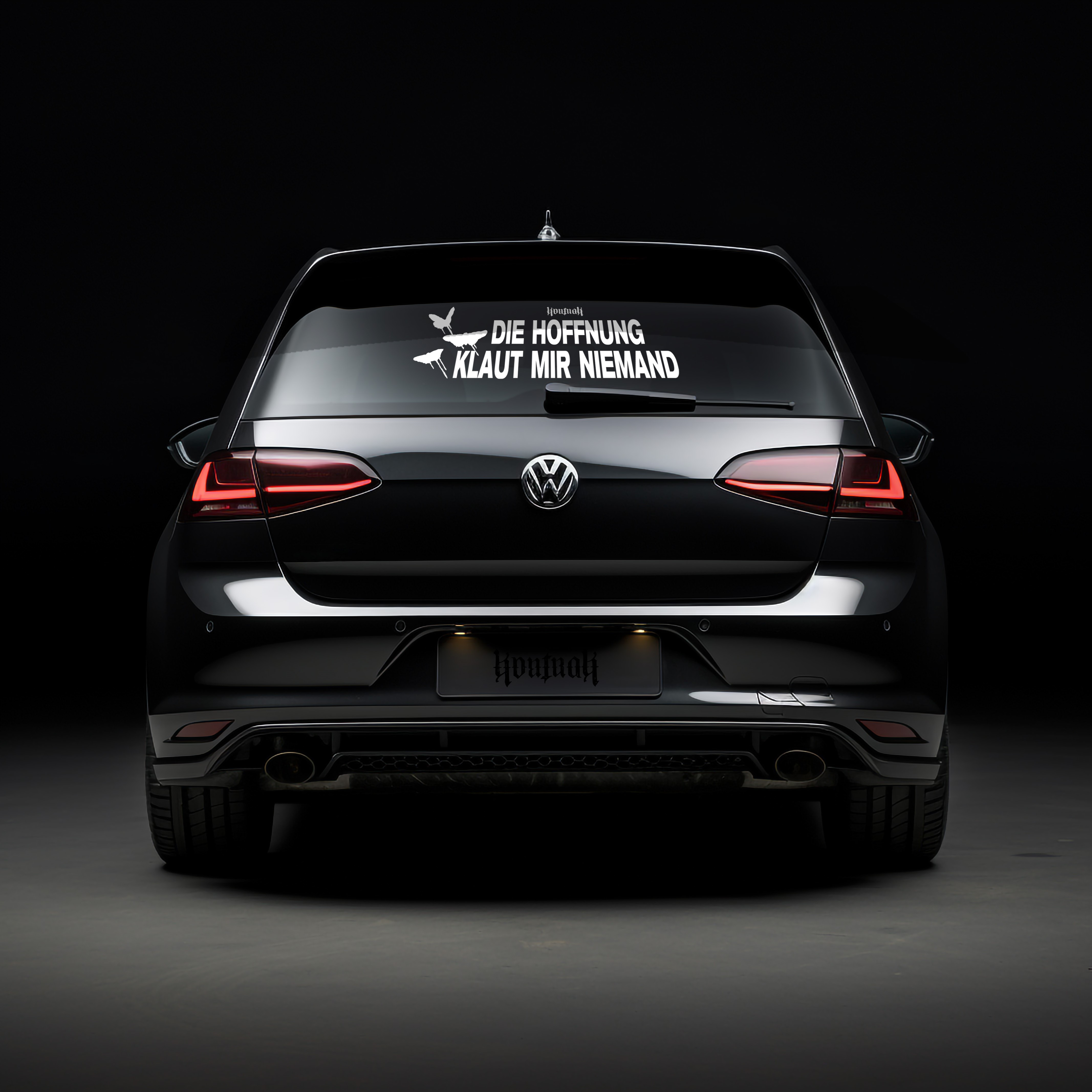 Ein schwarzes Auto mit einem Aufkleber auf der Heckscheibe mit dem Text 'DIE HOFFNUNG KLAUT MIR NIEMAND'.
