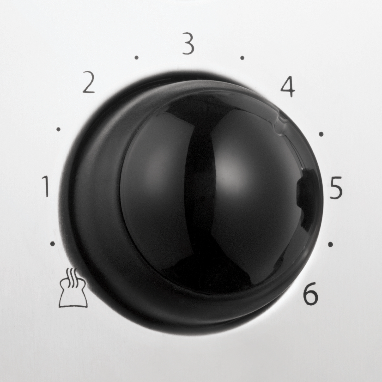 Close-up of a black knob with numbers from 1 to 6. It is on a white surface.