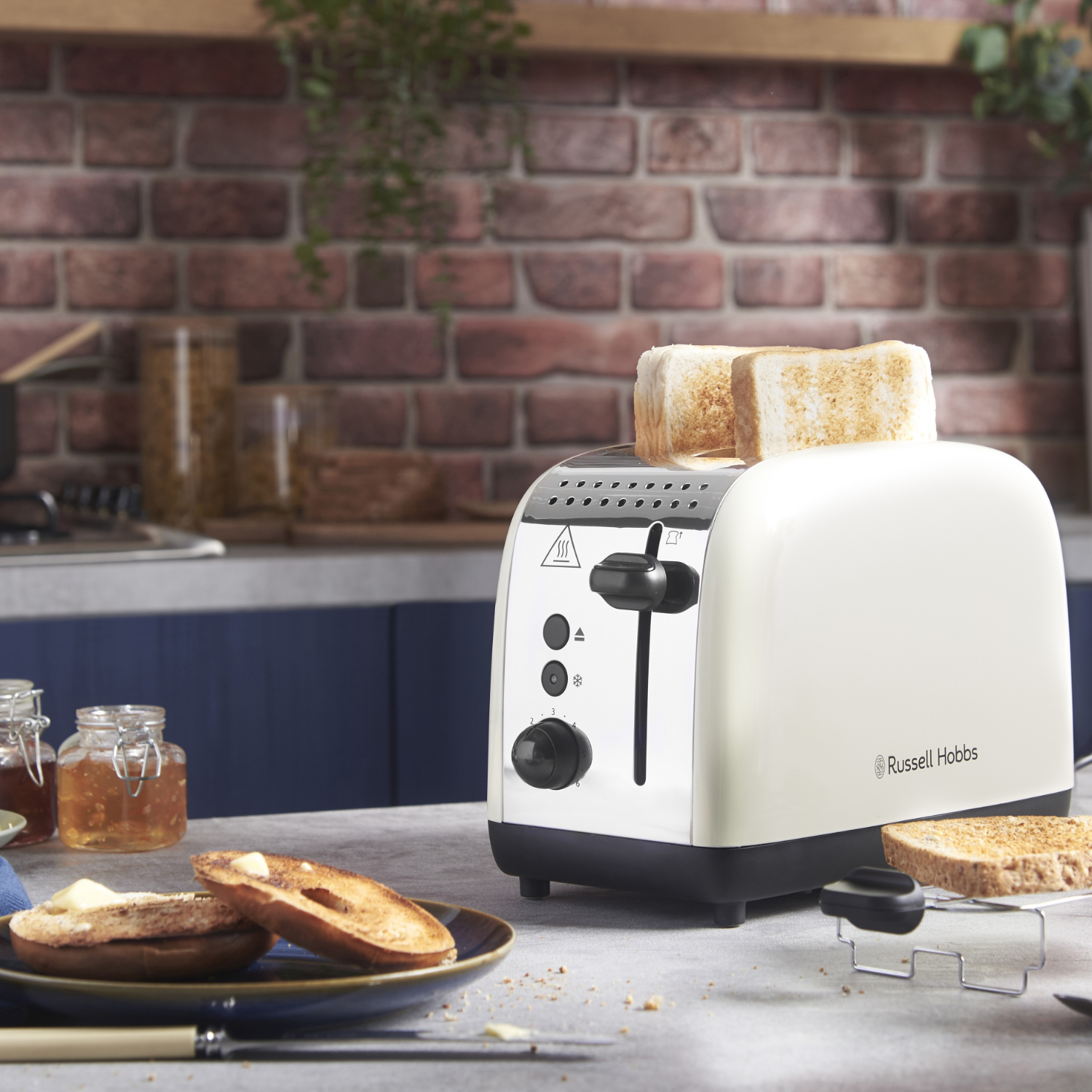 White toaster with toast, bread, butter, and jam on table, home setting.