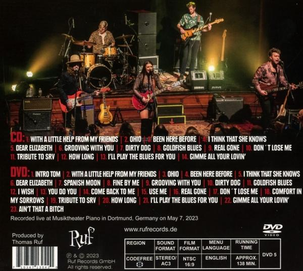 CD- und DVD-Cover mit einer Gruppe von Musikern, die live auf der Bühne spielen, Textelemente vorhanden.