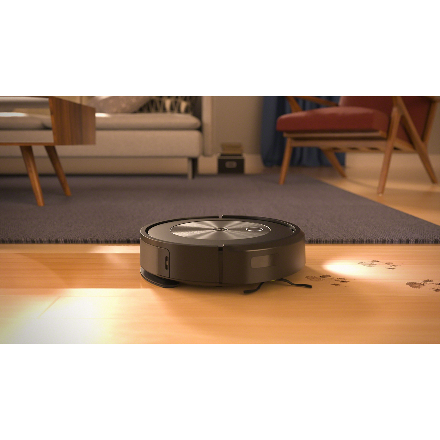 Een zwarte robotstofzuiger op een houten vloer in een kamer met een kleed en meubels.