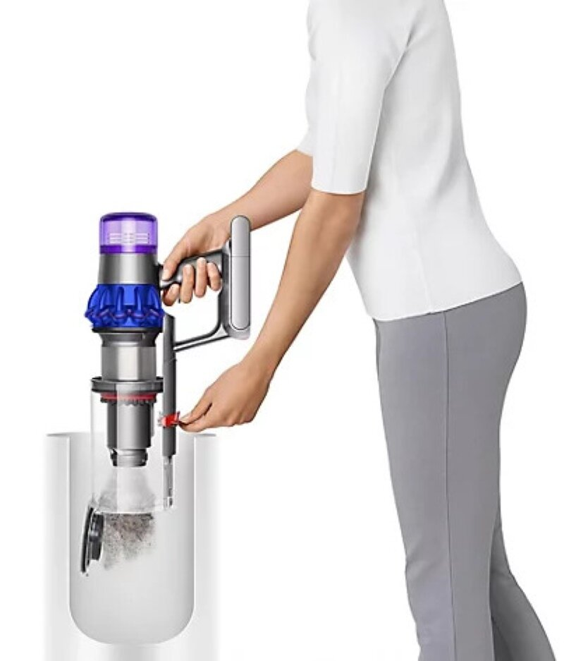 Kobieta używa odkurzacza ręcznego. Odkurzacz jest srebrny, fioletowy i niebieski. Jest biały pojemnik.