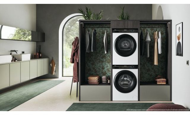 Modern bathroom with a washing machine and dryer, towels, and a mirror.