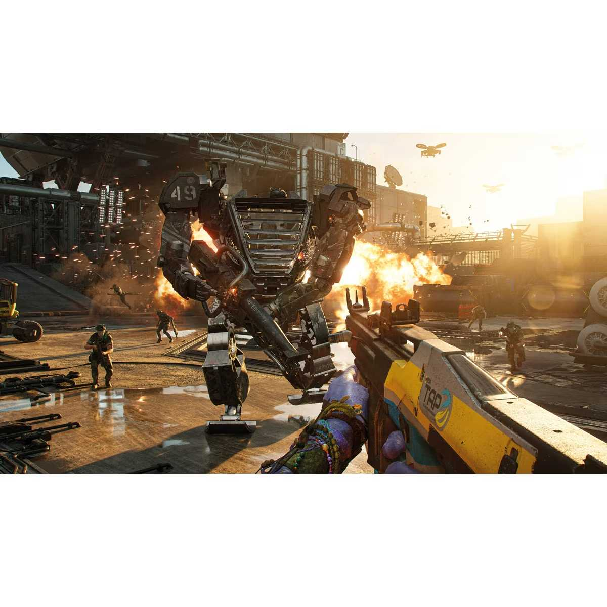 Vista en primera persona de una escena de batalla futurista en un videojuego, con un robot y soldados entre explosiones y fuego.