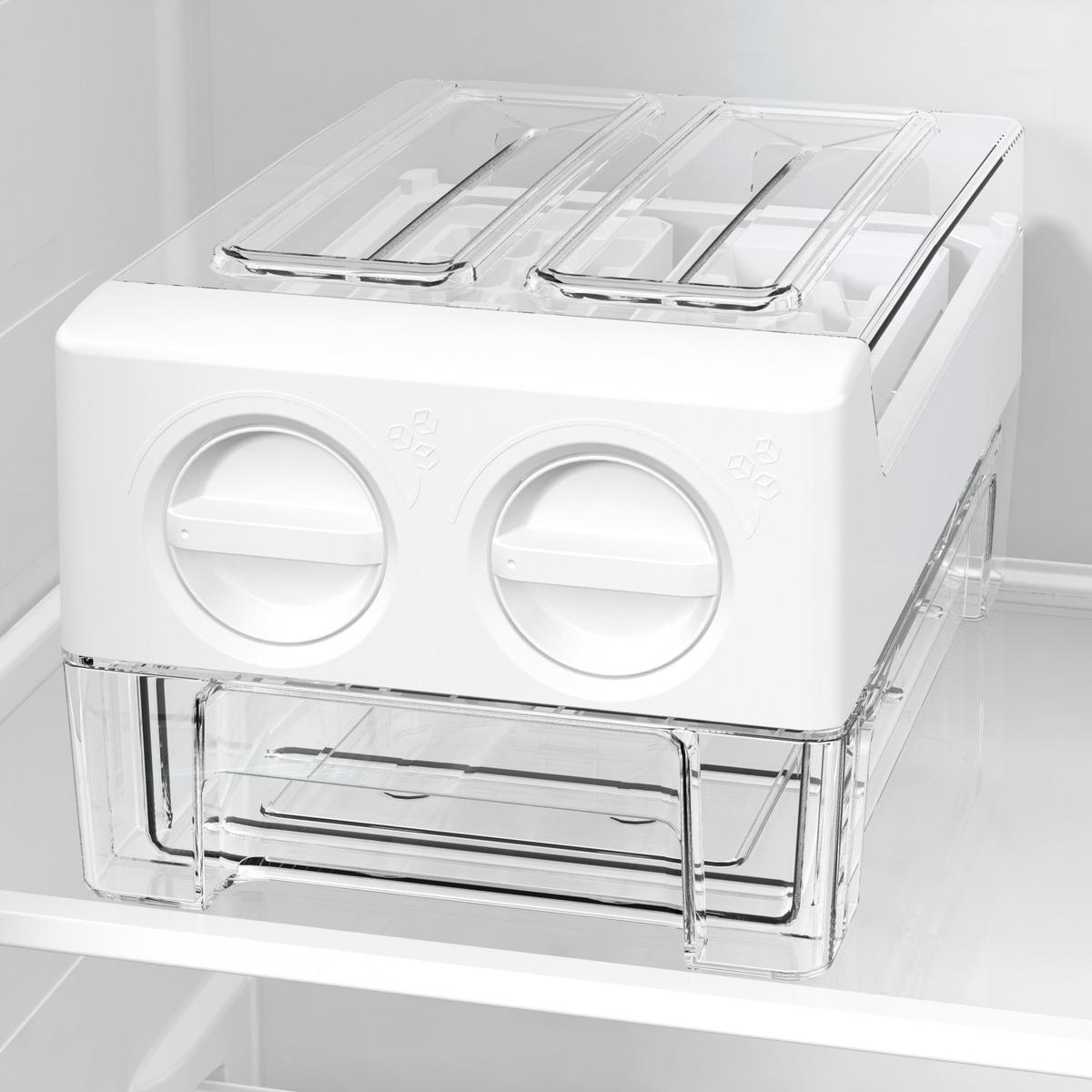 Ein weißer und durchsichtiger Kunststoff-Lebensmittelbehälter befindet sich in einem Kühlschrank. Er hat zwei Fächer mit Deckeln und zwei runde Griffe.