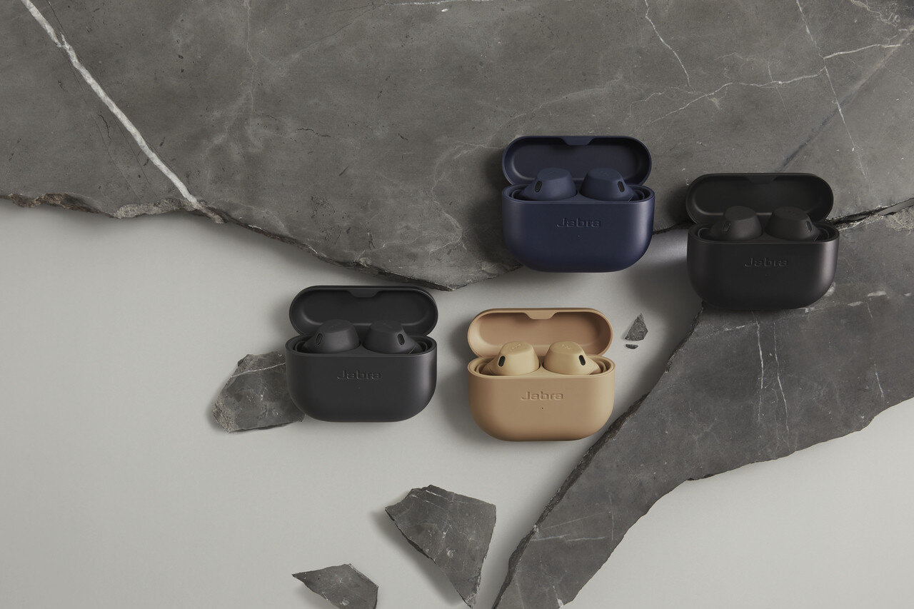 Cztery słuchawki Jabra w etui ładujących, ułożone na powierzchni przypominającej kamień.