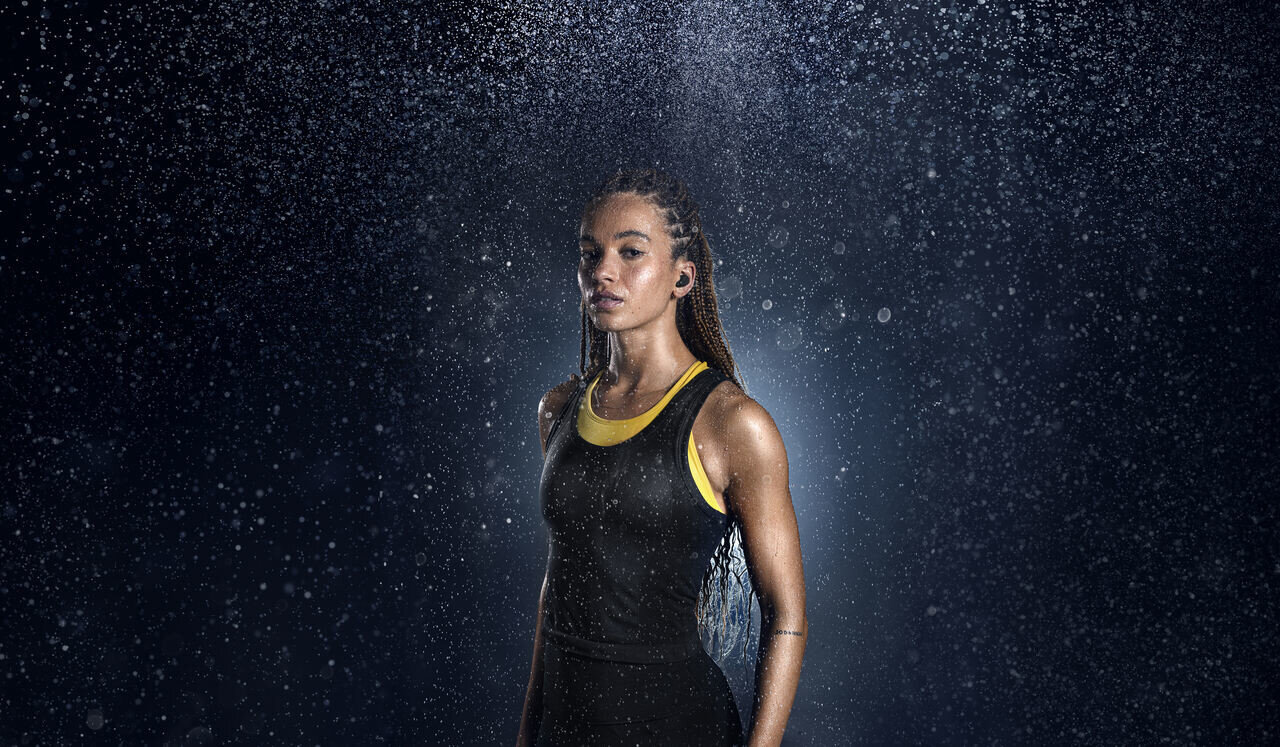 Kobieta w czarnym i żółtym topie w deszczu, nosząca słuchawki.