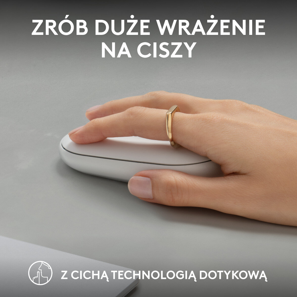 Ręka ze złotym pierścionkiem używająca białej myszy na szarej powierzchni. Tekst: Zrób duże wrażenie w ciszy.
