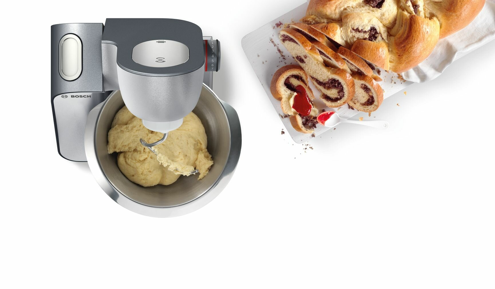 Srebrno-szara maszyna kuchenna z ciastem w misce i chlebem z nadzieniem czekoladowym po prawej stronie.