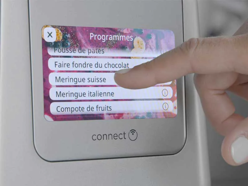 Palec dotyka ekranu z opcjami menu, "Meringue suisse" jest podświetlone.