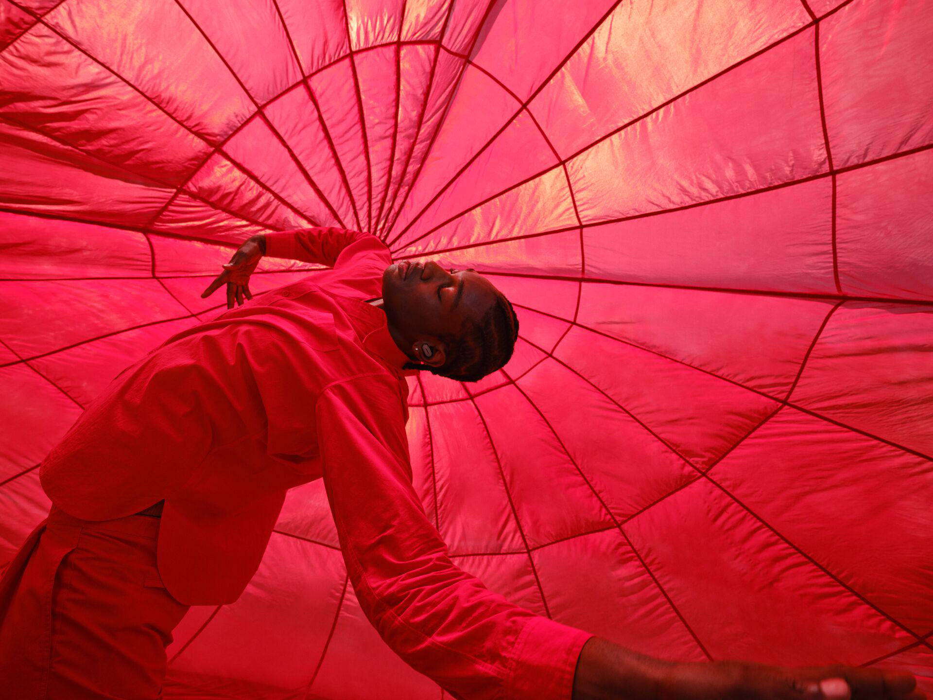 Person in roter Kleidung unter roter Struktur.