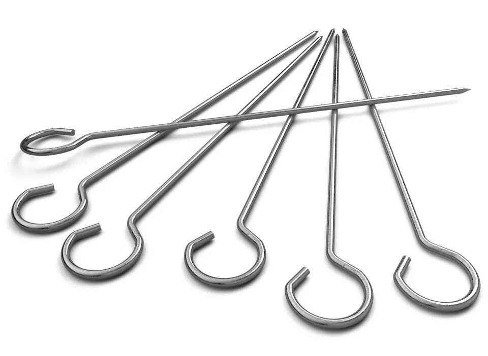 Zestaw metalowych szpikulców z pętlami, ułożonych na białej powierzchni.