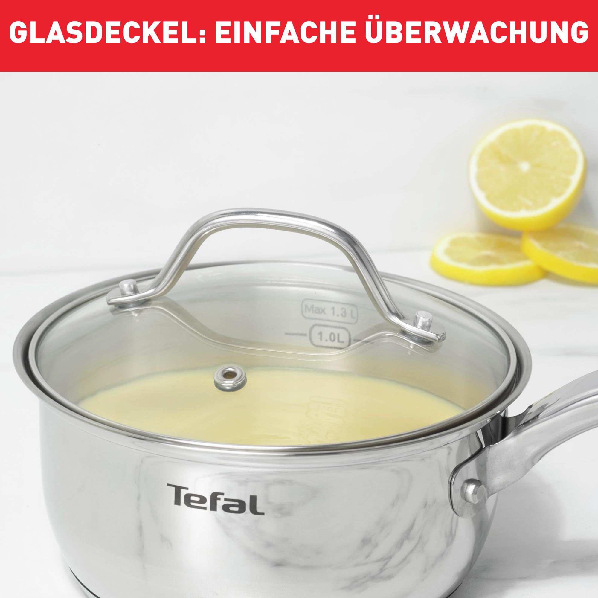 Ein Edelstahl-Topf mit Glasdeckel, der Flüssigkeit enthält, und zwei Zitronenscheiben daneben.
