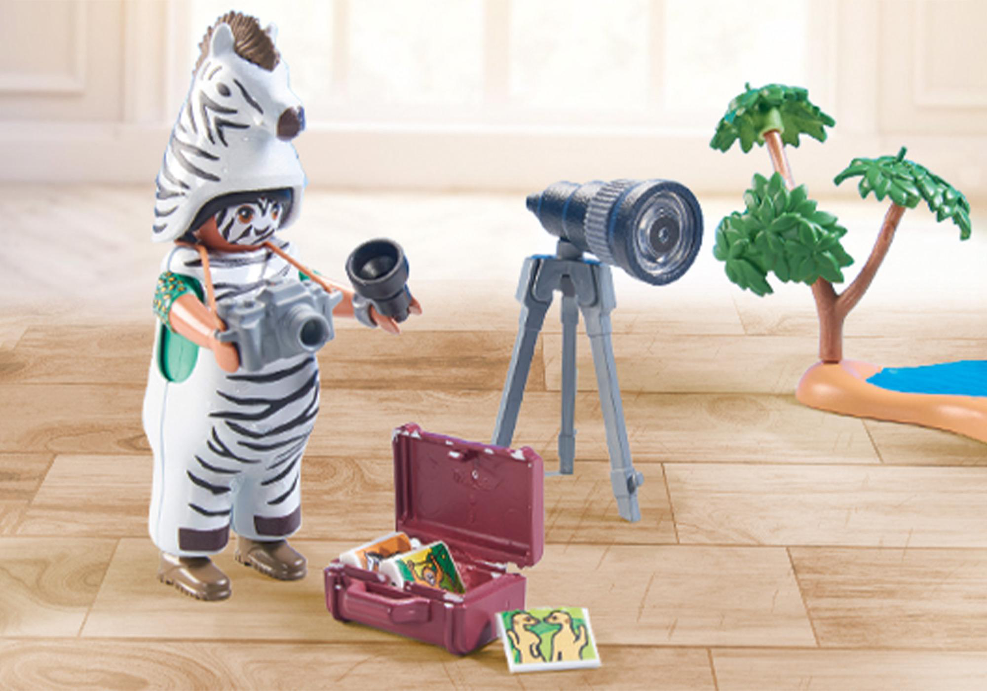 Eine Playmobil-Figur als Zebra verkleidet, macht ein Foto mit einer Kamera und einem Fernglas.