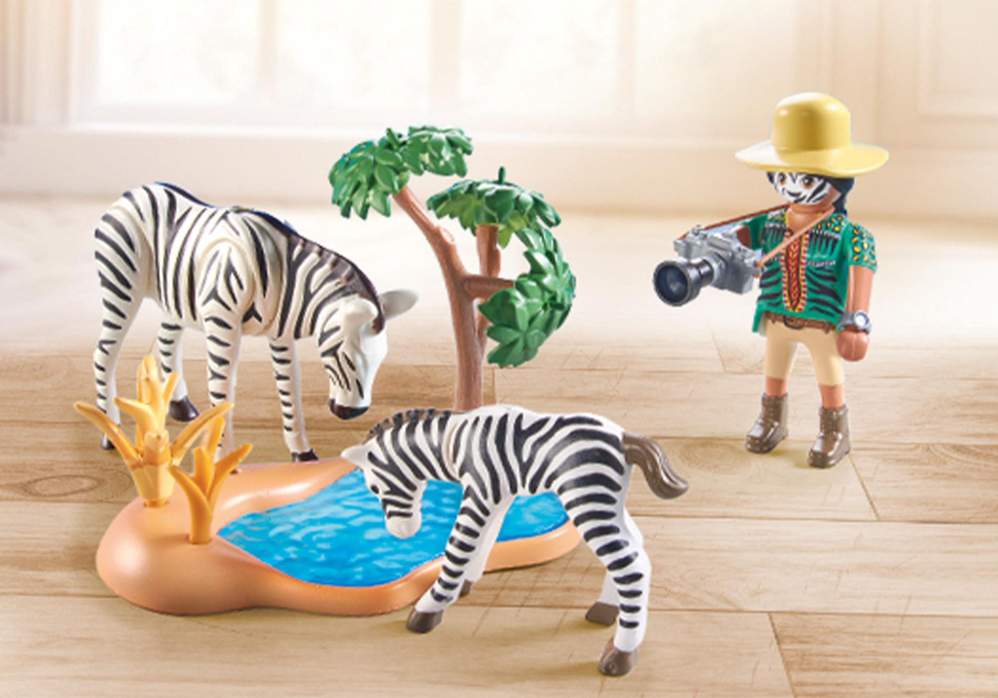 Playmobil Safari-Szene: Zebras und ein Fotograf in der Nähe eines Wasserlochs auf Holz.