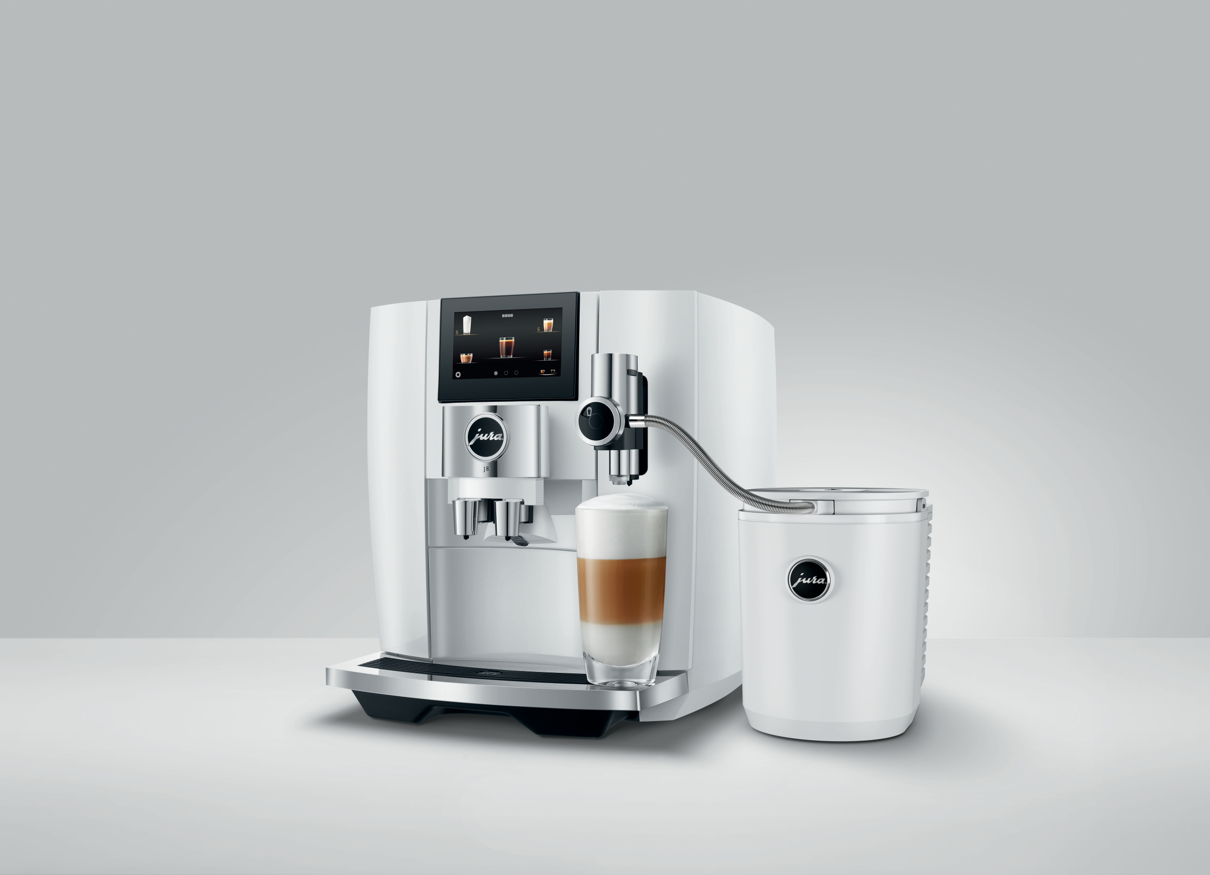 Weiße Jura Kaffeemaschine mit einem Glas Latte. Weißer Hintergrund, graue Oberfläche.