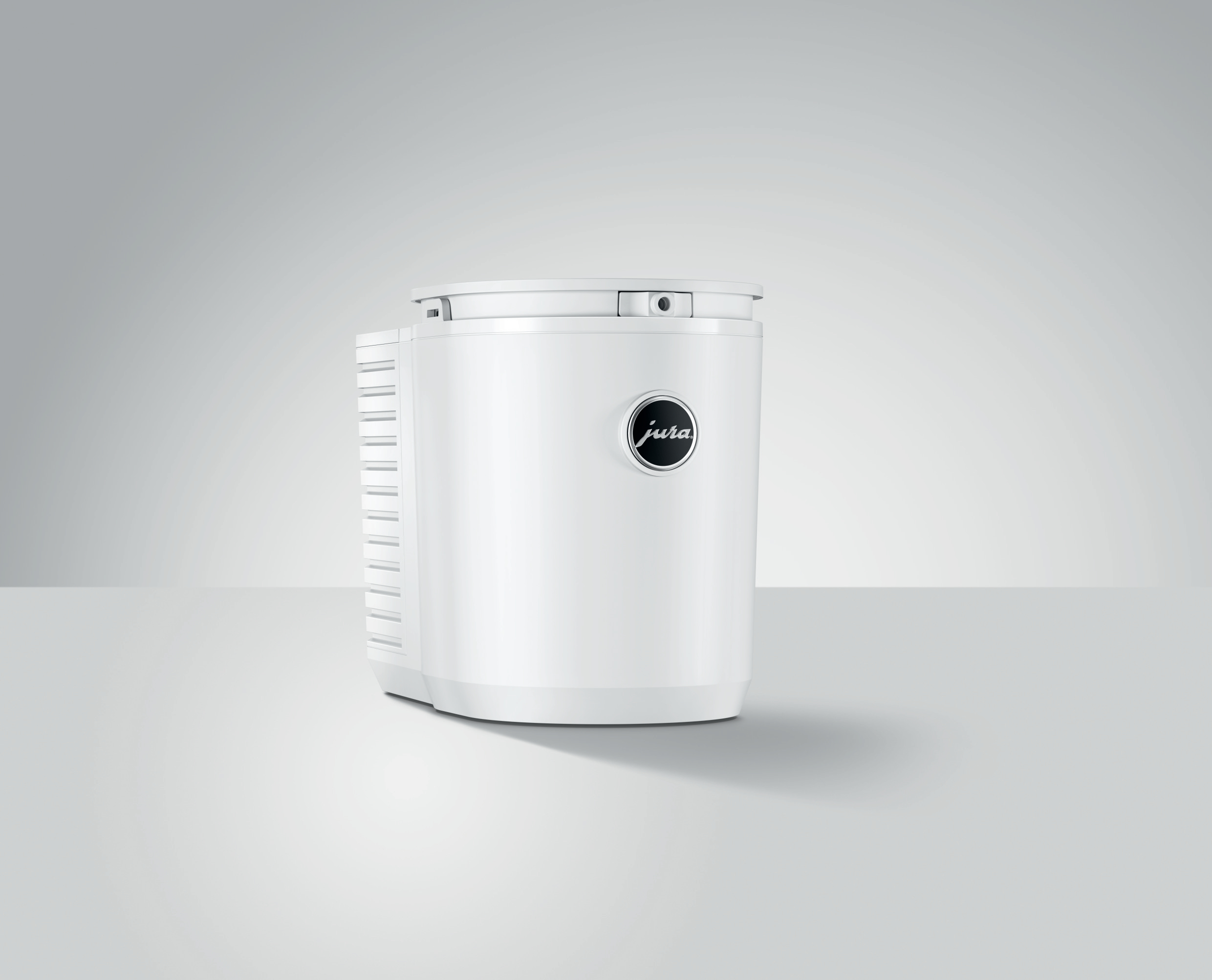 Weißer Kaffeeautomat mit schwarzem kreisförmigen Logo auf der Vorderseite, vor hellgrauem Hintergrund.